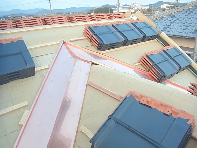 富山の住宅で屋根の継ぎ目や外壁との取り合いに金属板金を施工し雨水の流れを整えている様子